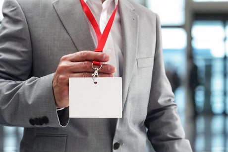 person in a suit holding up a tradeshow badge
